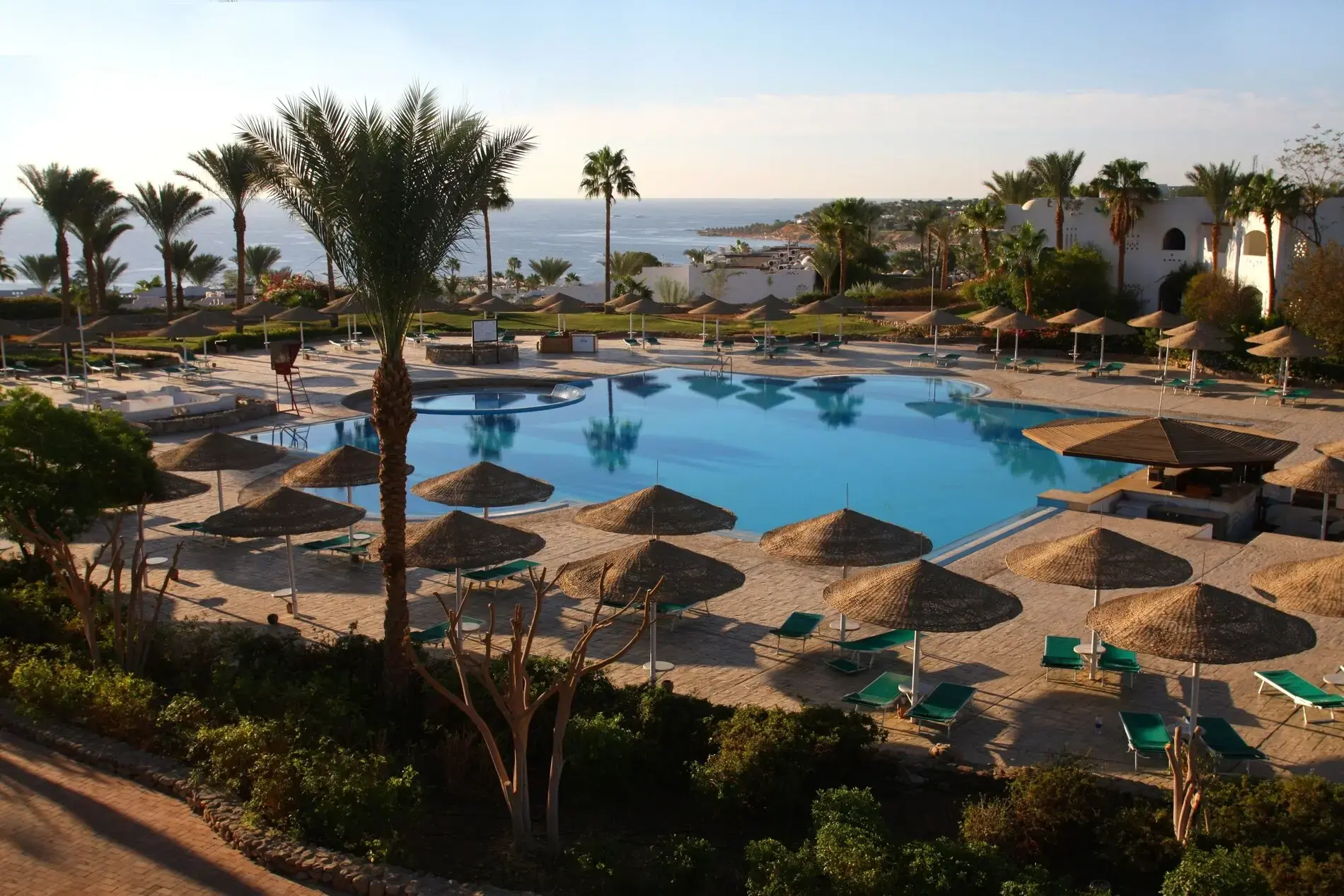 Открит басейн с чадъри и палми и изглед към морето през деня – Domina Coral Bay Aquamarine Beach, Шарм Ел Шейх