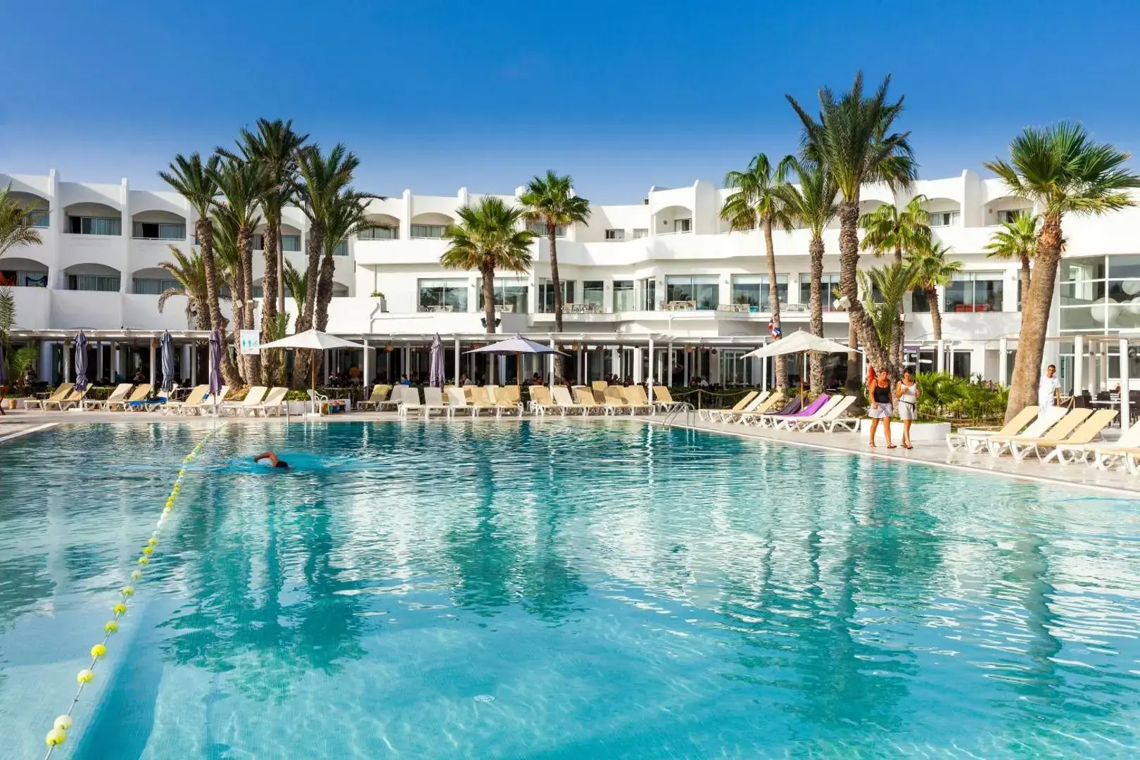Голям открит басейн с шезлонги под палмите в слънчев ден – Palm Beach Club Djerba, Джерба