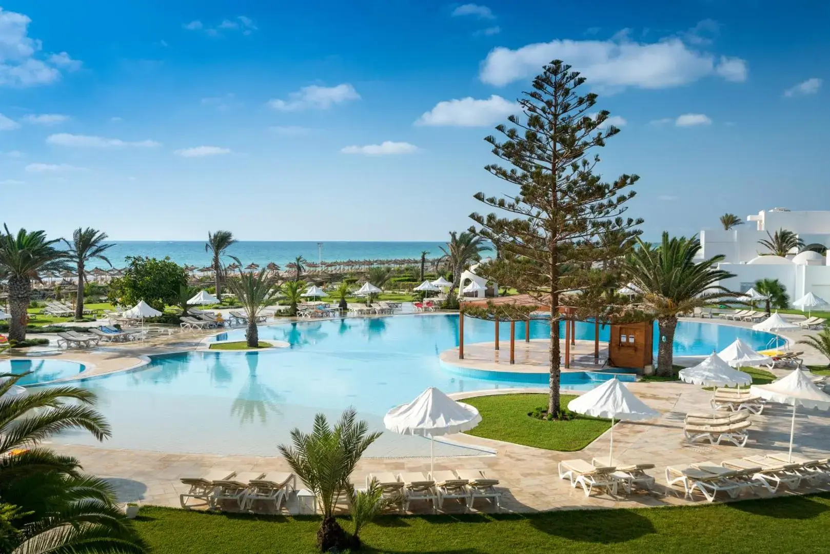 Басейн тип лагуна с шезлонги, палми и изглед към морето – Iliade Aqua Park Djerba, Джерба