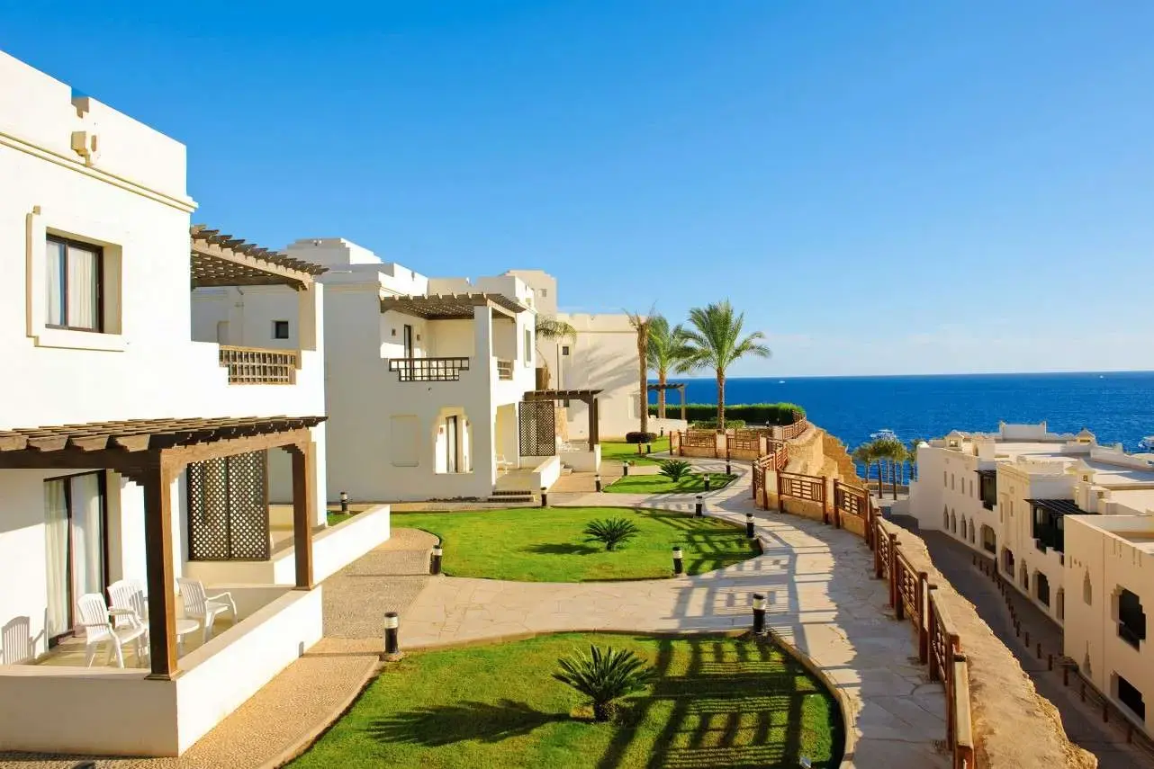 Бели сгради със стаи, тераси и зелена морава с изглед към морето – Sharm Resort, Шарм Ел Шейх