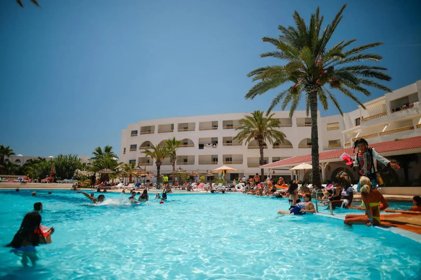 Гости плуват в басейна под палмите – Blumar Resort & Spa, Ясмин Хаммамет