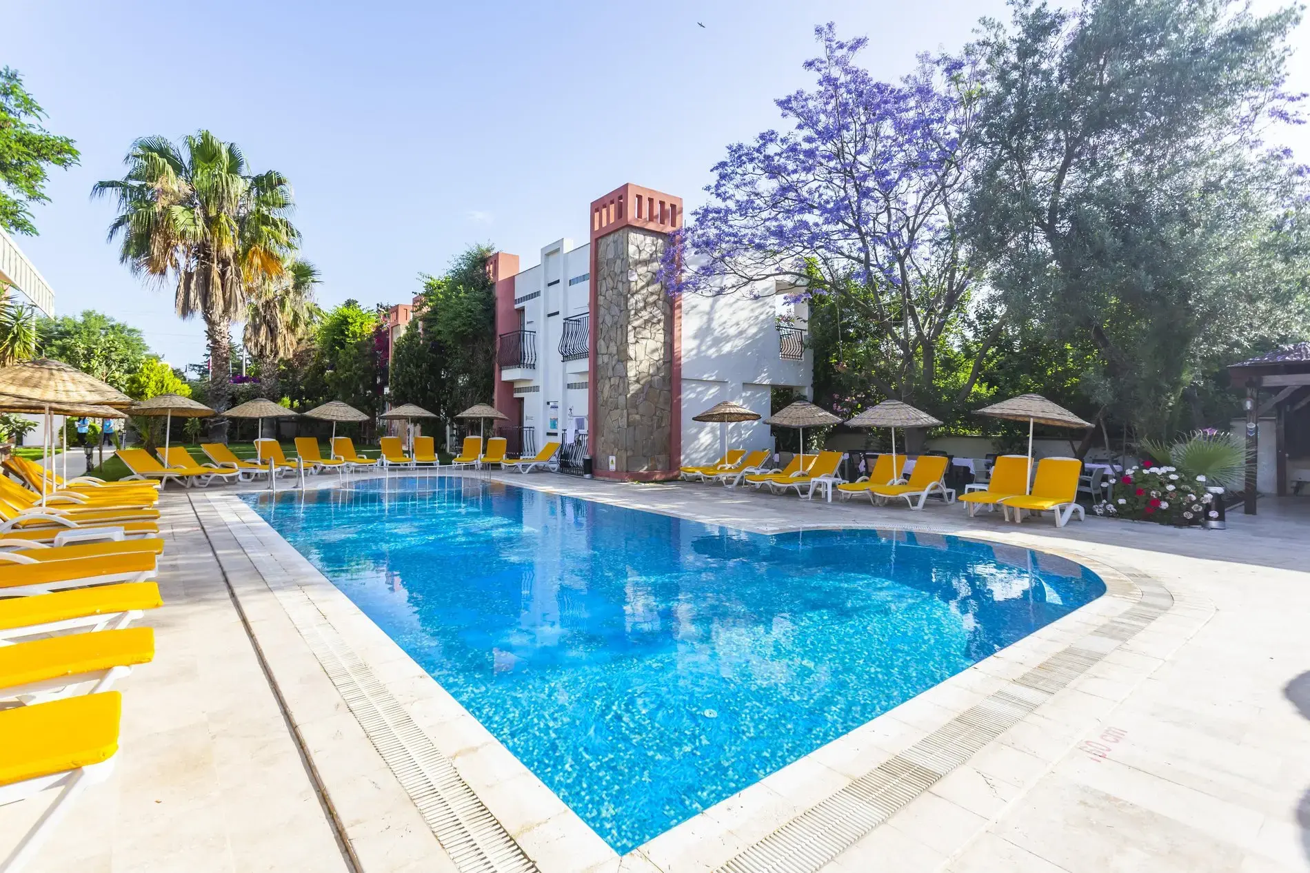 Хотелът с басейна, жълти шезлонги и сламени чадъри сутрин – Kriss Hotel, Бодрум
