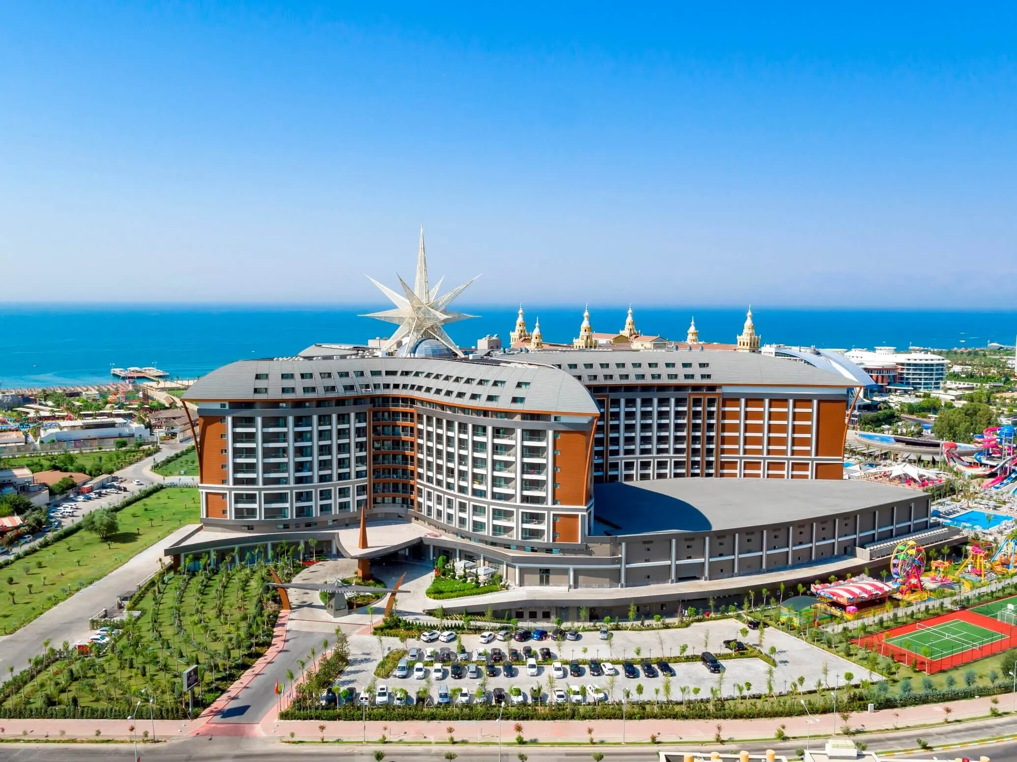 Хотелската сграда с тематична звезда на покрива и морето зад нея – Royal Seginus Hotel, Лара Кунду