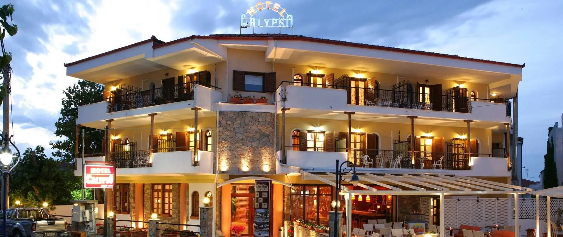 Осветената фасада на хотела с балкони по здрач – Calypso Hotel, Касандра