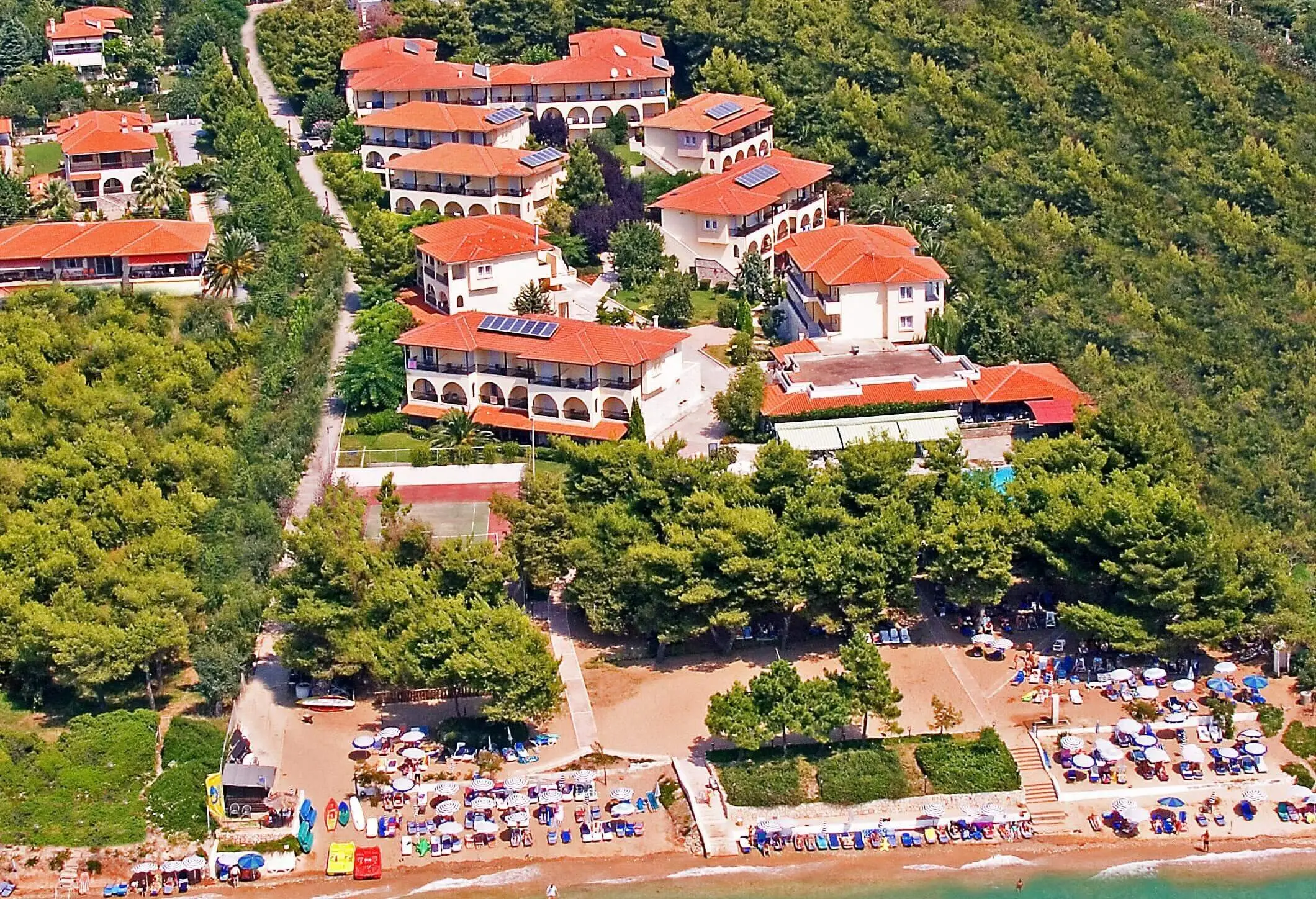 Сградите с червени покриви сред боровата гора от въздуха – Portes Beach Hotel, Касандра