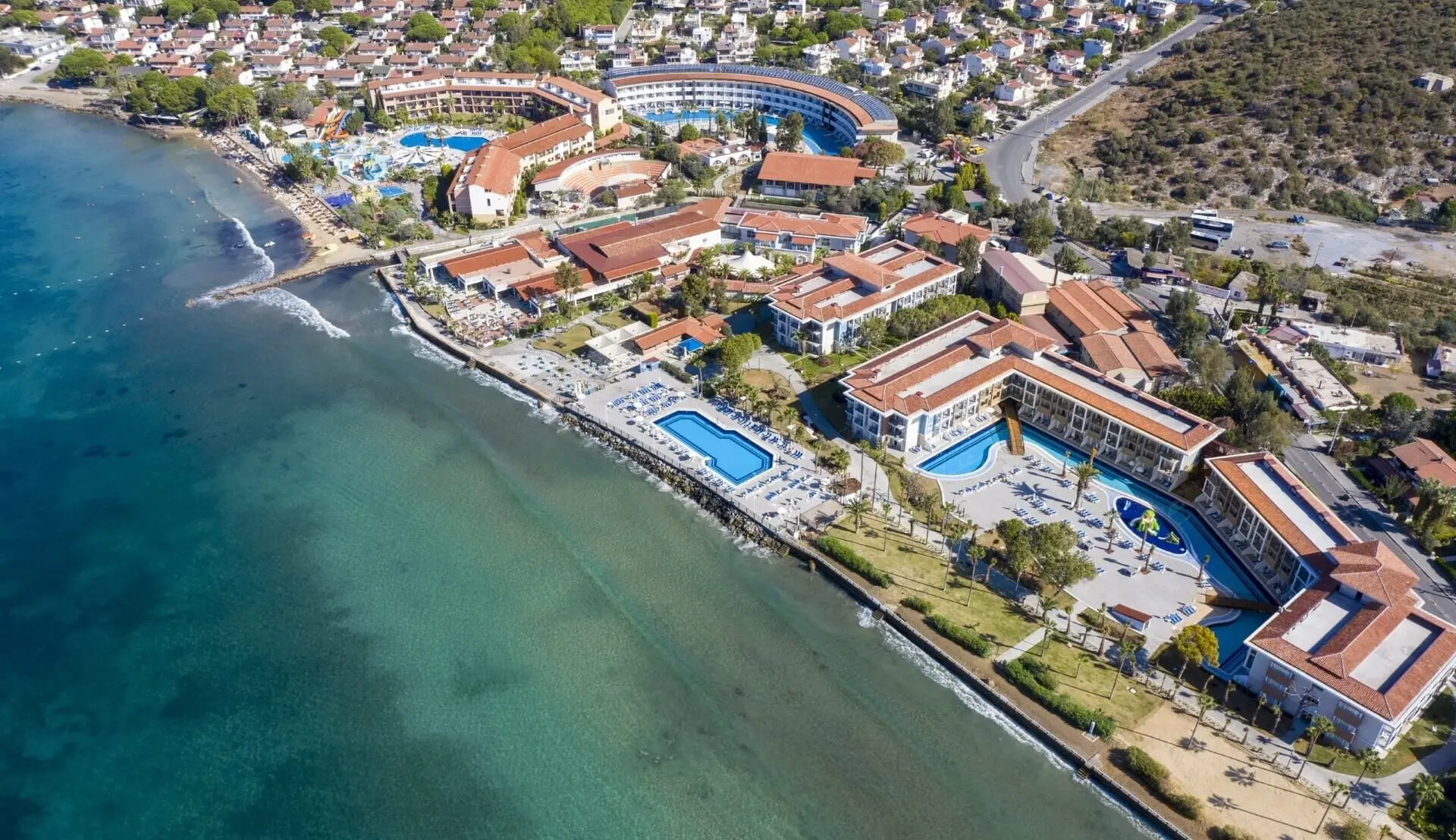 Комплексът отвисоко с басейни и червени покриви по брега на залива – Ephesia Holiday Beach Club, Кушадасъ