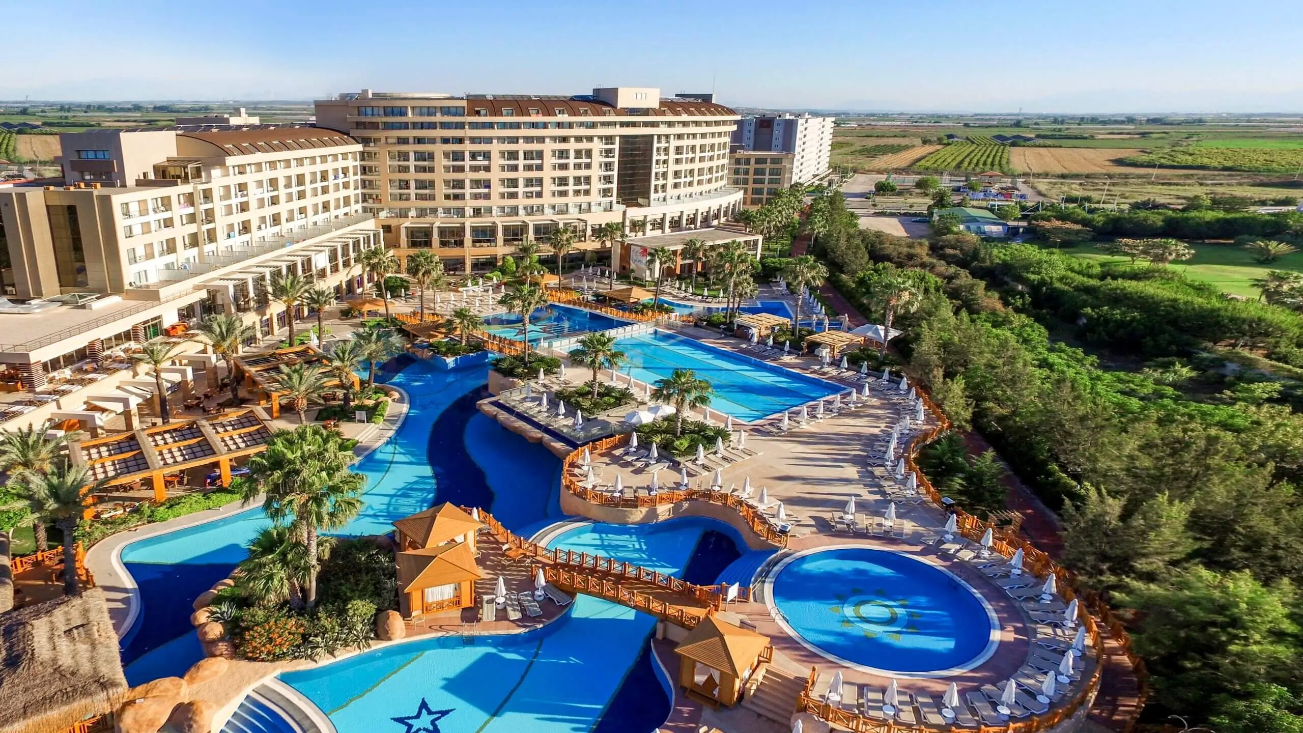 Басейни с водни пързалки и корпусите на хотела отвисоко – Fame Residence Lara & SPA, Лара