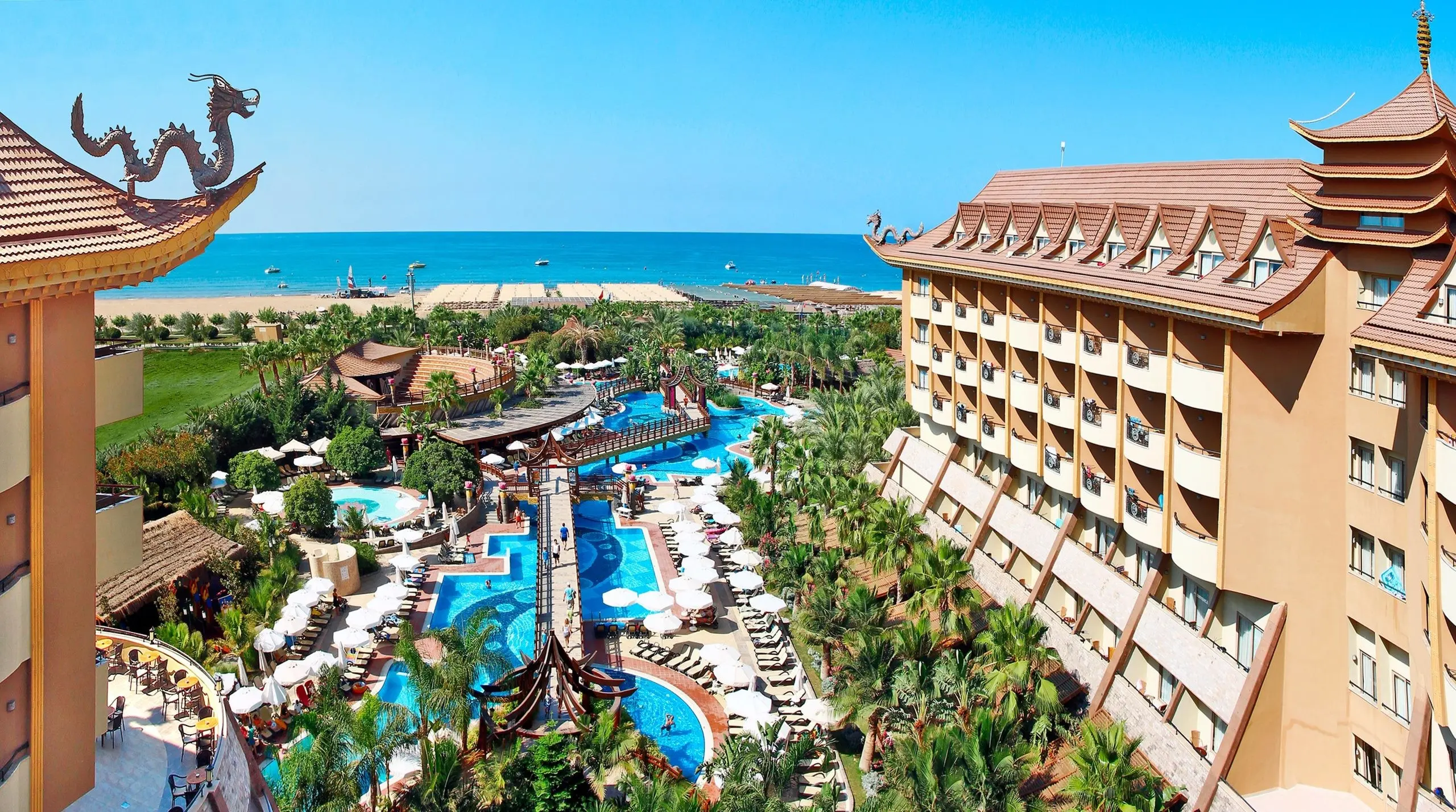Хотелът на морския бряг с басейни, палми и главен корпус отгоре – Royal Dragon Hotel, Сиде