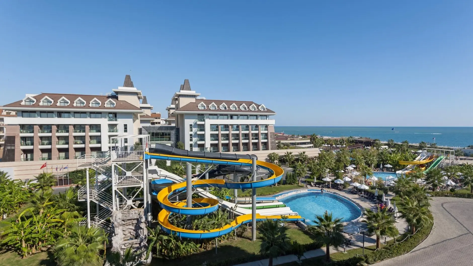 Аквапарк с цветни водни пързалки и басейн пред сградата на хотела – Sherwood Dreams Resort, Белек