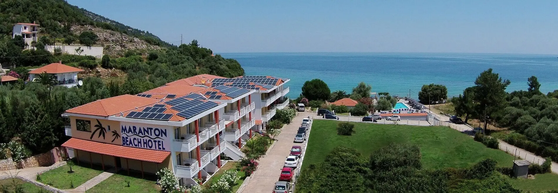 Сградата на хотела със соларни панели и морето зад нея – Maranton Beach Hotel, Тасос