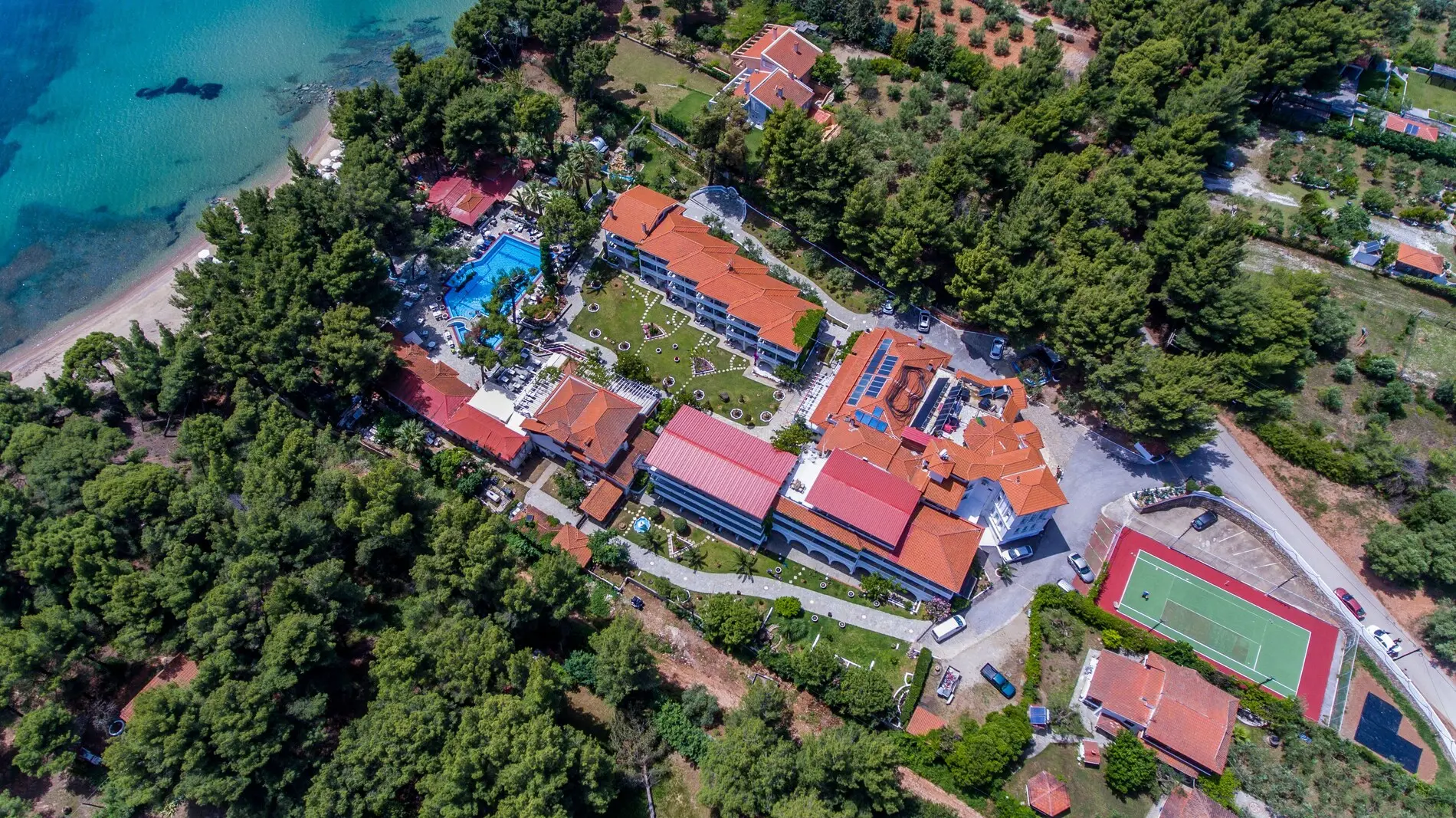 Въздушен изглед към корпусите сред боровете, басейна и корта – Porfi Beach Hotel, Ситония