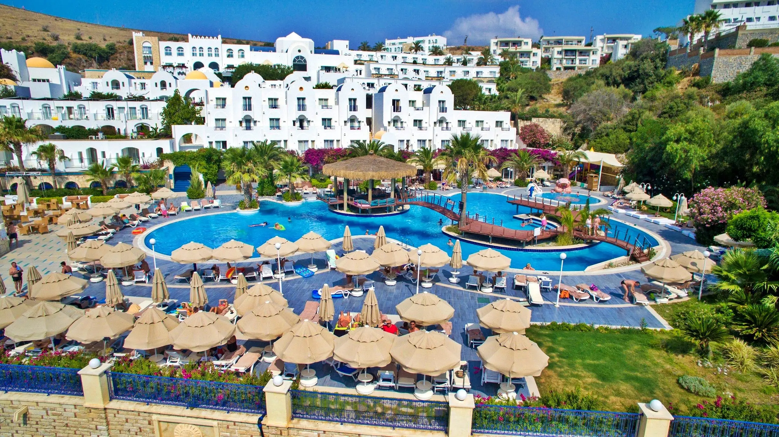 Басейн със сламени чадъри и бели къщи в средиземноморски стил – Salmakis Resort & Spa, Бодрум