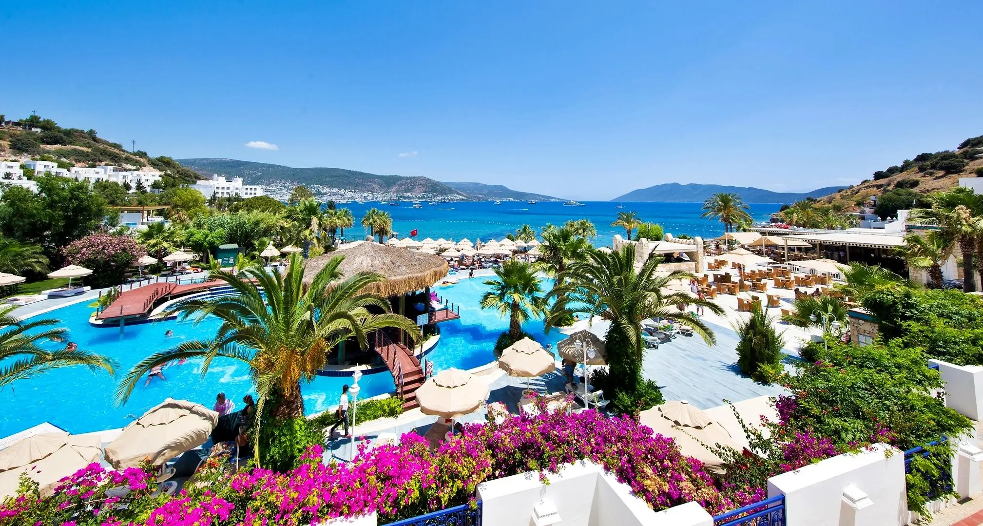 Басейн сред палми и цъфнали бугенвилии с изглед към залива – Salmakis Resort & Spa, Бодрум