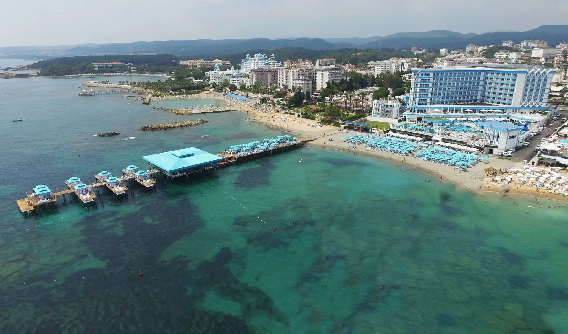 Въздушна снимка на плажа с дълъг кей и тюркоазено море пред хотела – Granada Luxury Beach Avsallar, Алания