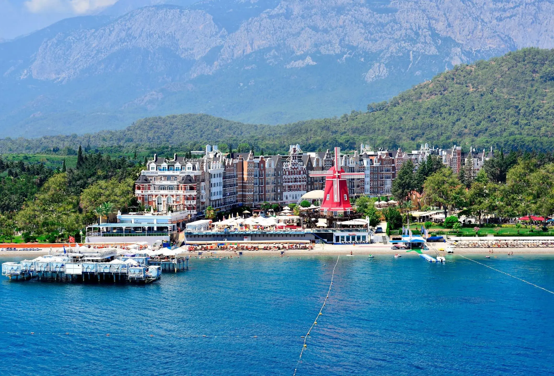 Панорамен изглед към хотела, кея и плажа с планините Торос зад тях – Orange County Resort Hotel Kemer, Кемер