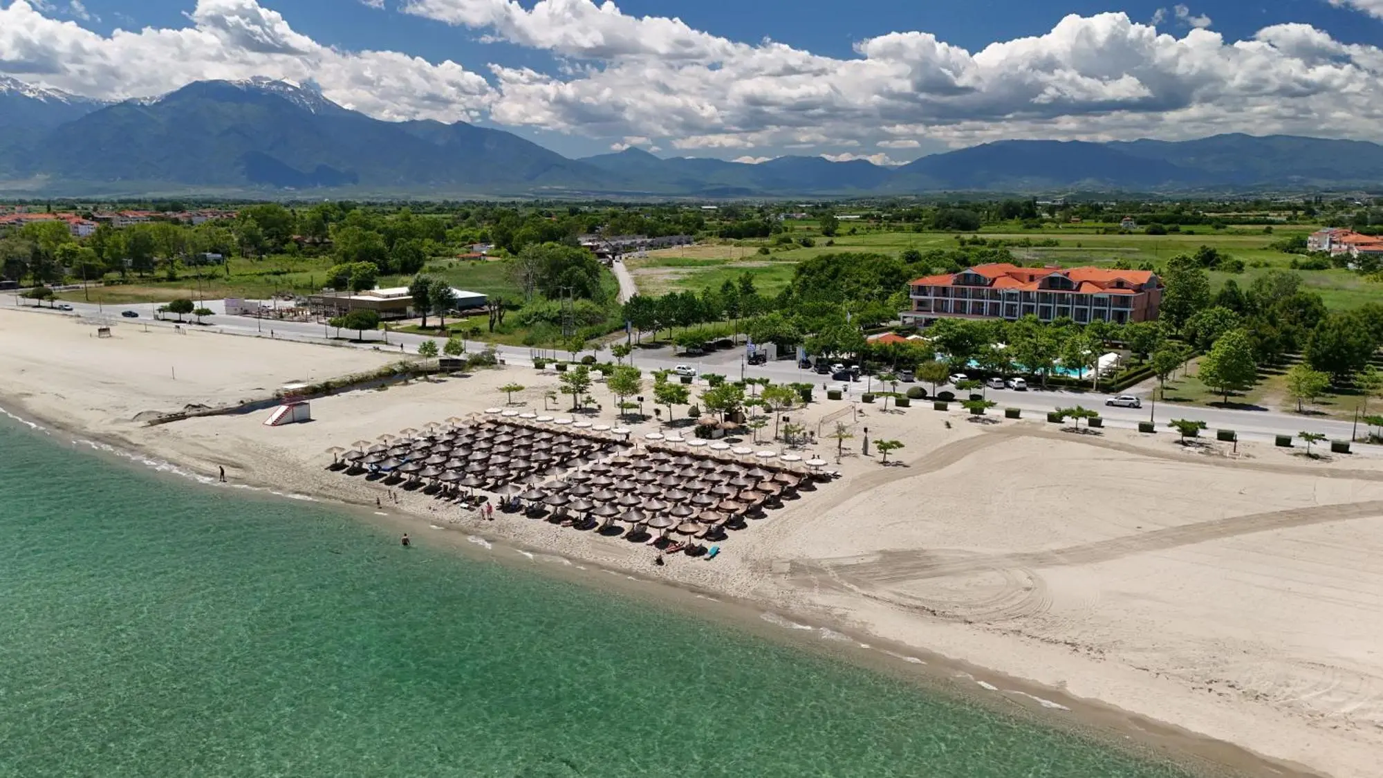 Отгоре: плажът с чадъри, хотелът и планините зад него – Giannoulis Hotel, Олимпийска ривиера